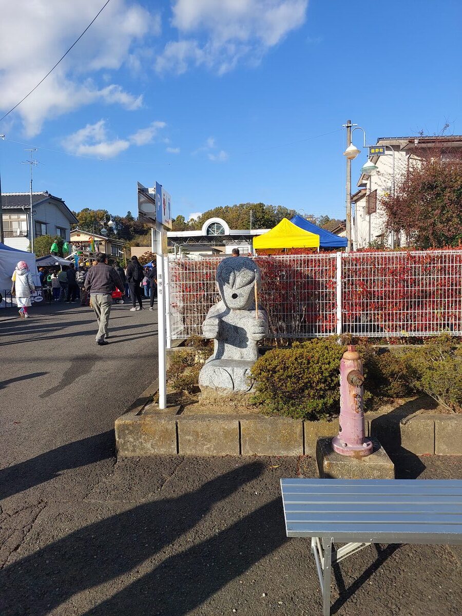A stone alien statue stands beside a road in Iino-machi, a permanent fixture of the town's UFO identity