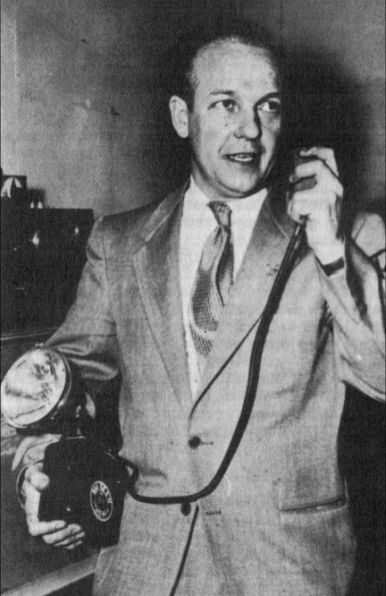 John Otto, Director of Investigation, holding the portable light beam transmitter, 1955
