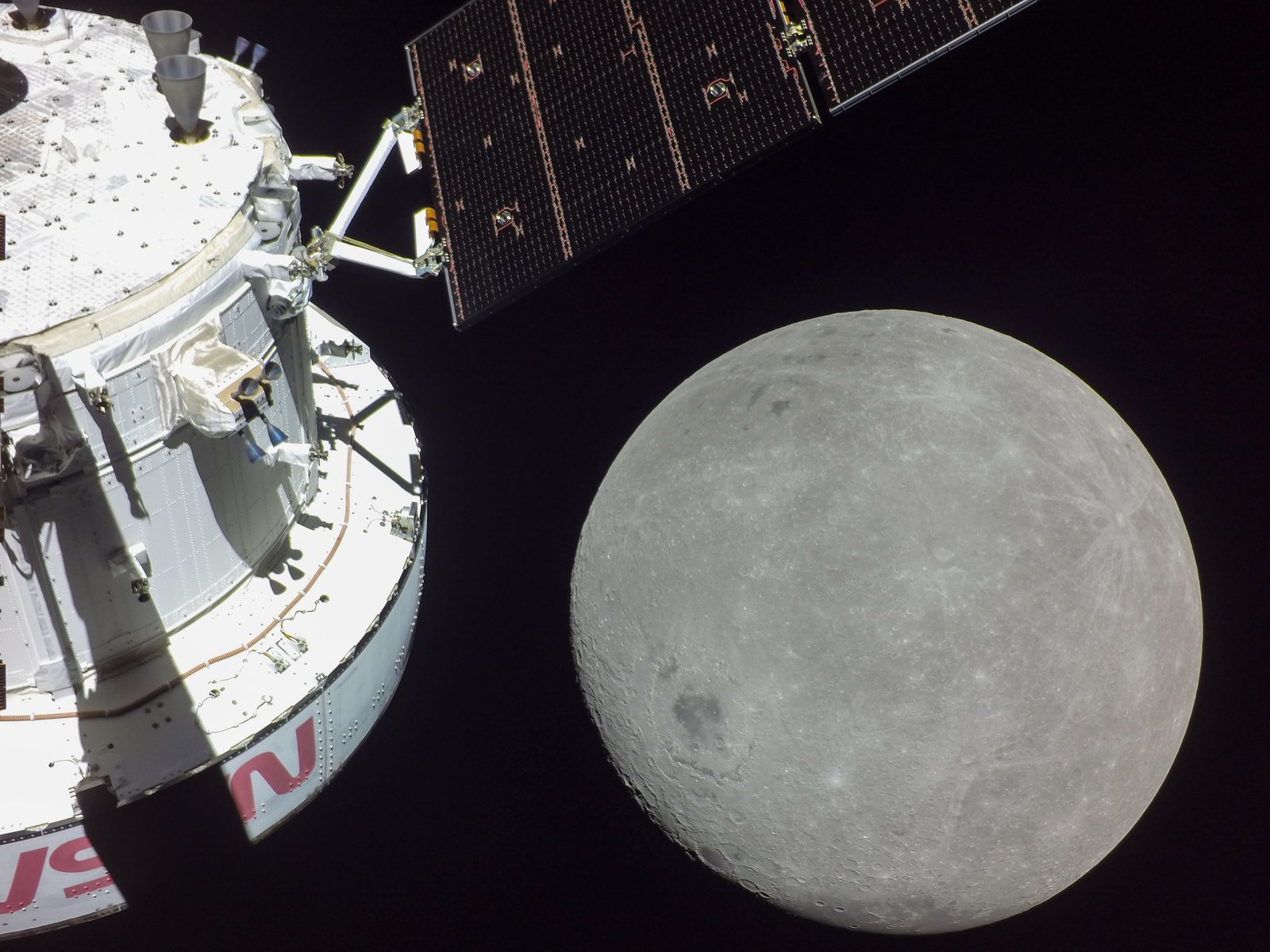 NASA's Orion spacecraft during an Artemis I flyby of the Moon, the lunar surface below and Earth in the distance.