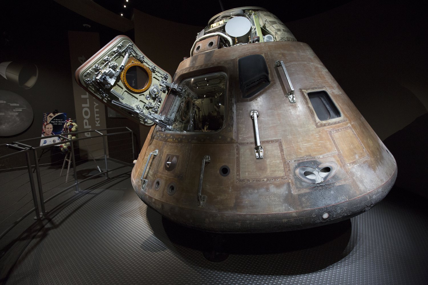 The Apollo 14 command module Kitty Hawk on display with a memorial wreath placed beside it.