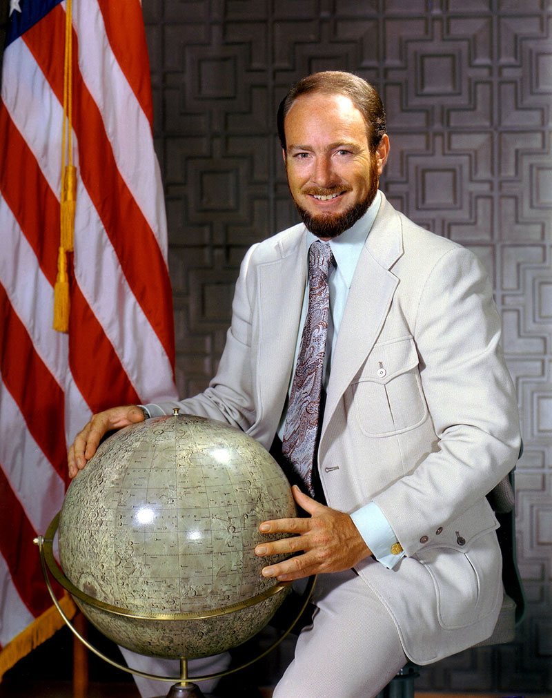 Edgar Mitchell in his 1971 Apollo 14 official NASA portrait, in a white spacesuit holding his helmet.